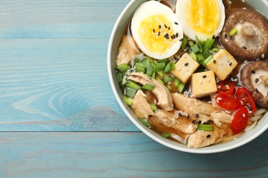 Photo of Bowl of delicious ramen on light blue wooden table, top view with space for text. Noodle soup