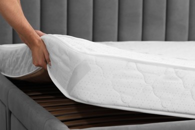 Man putting soft mattress on bed, closeup