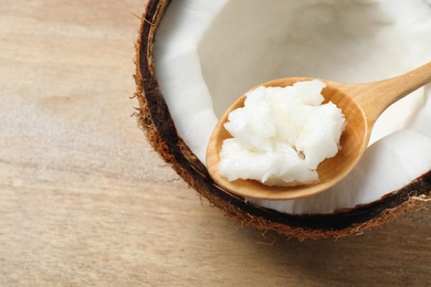 Photo of Ripe coconut and spoon with oil on table, closeup. Healthy cooking