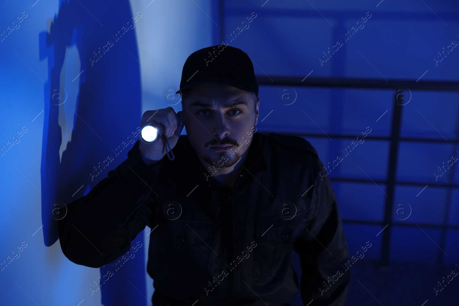 Photo of Male security guard with flashlight in dark room