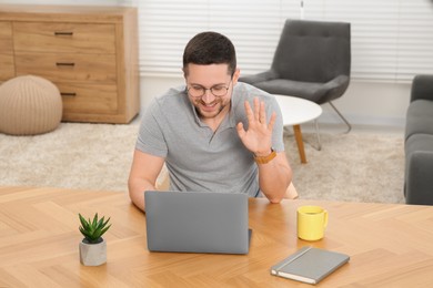 Photo of Man having video chat via laptop at wooden table at home