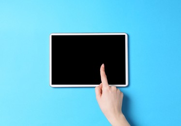 Photo of Online store. Woman using tablet on light blue background, top view