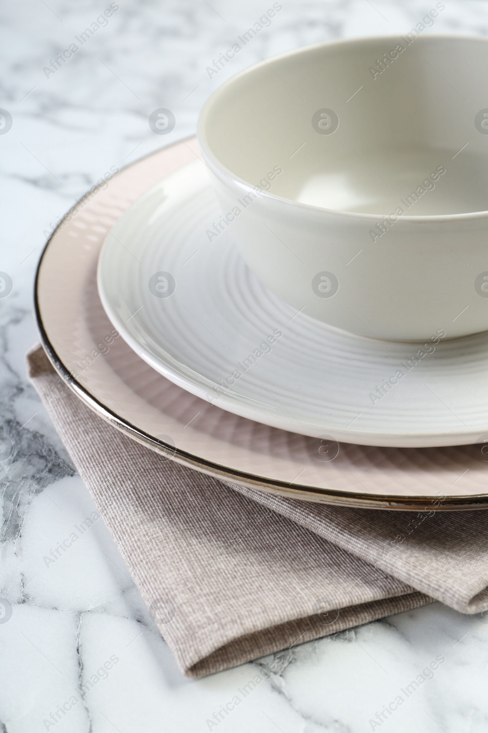 Photo of Clean plates, bowl and napkin on table, closeup