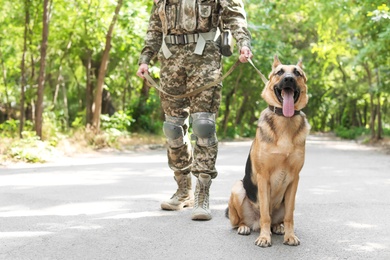 Man in military uniform with German shepherd dog outdoors
