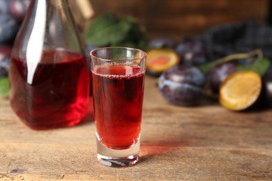 Delicious plum liquor on wooden table. Homemade strong alcoholic beverage