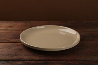 Photo of Beautiful beige ceramic plate on wooden table