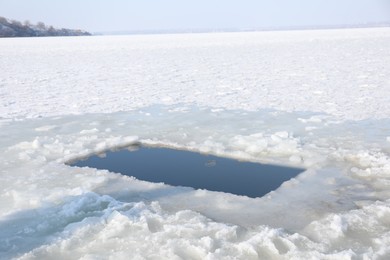 Photo of Ice hole in river on winter day. Baptism ritual