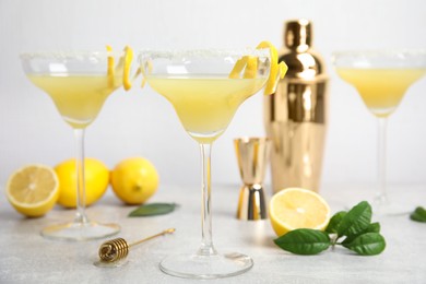 Photo of Delicious bee's knees cocktails and ingredients on light grey table