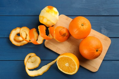 Photo of Orange fruits with peels on blue wooden table, flat lay