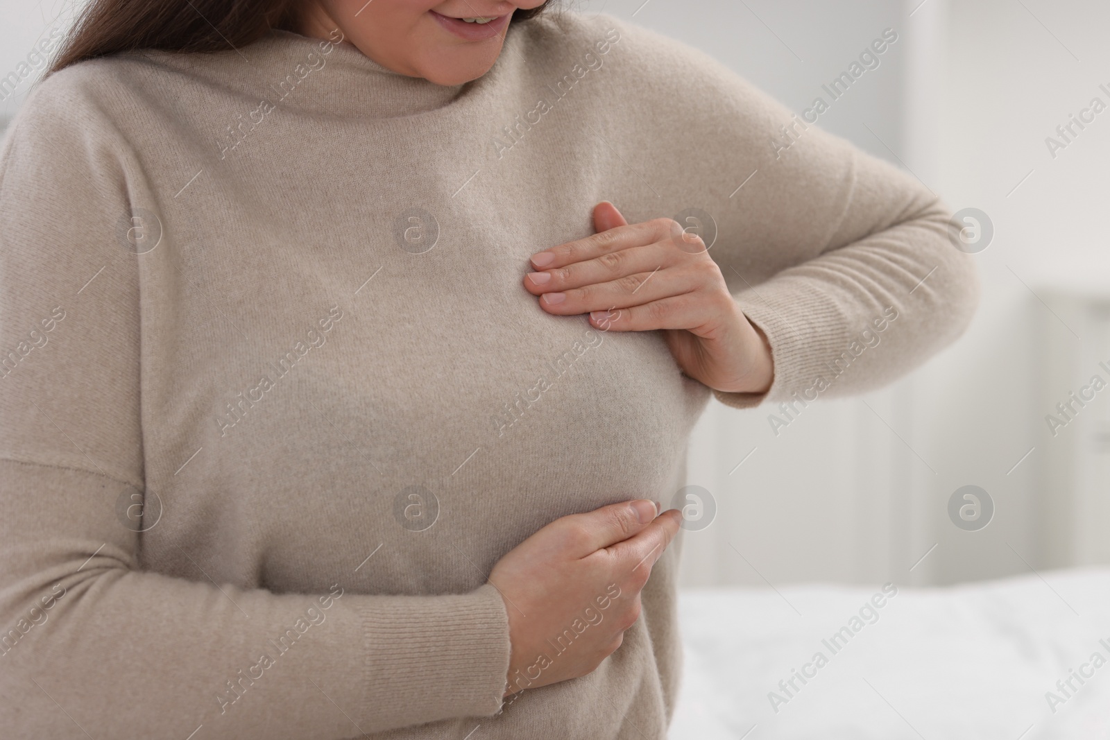 Photo of Mammology. Woman doing breast self-examination indoors, closeup