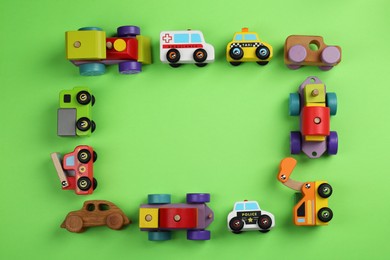 Photo of Frame of different toy vehicles for children on green background, flat lay. Space for text