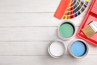 Photo of Flat lay composition with cans of paint, brush and renovation tools on white wooden background. Space for text