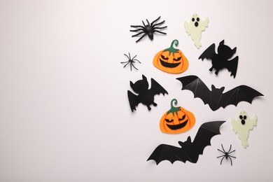 Photo of Flat lay composition with bats, pumpkins, ghosts and spiders on white background, space for text. Halloween celebration
