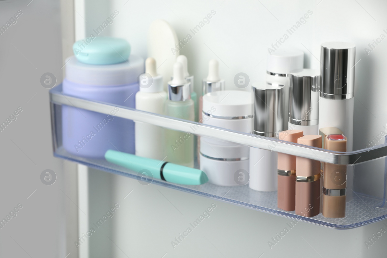 Photo of Different cosmetic products on shelf in refrigerator