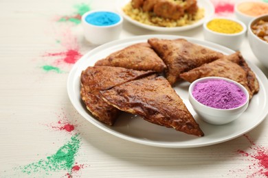 Photo of Traditional Indian food and color powders on white wooden table. Holi festival celebration