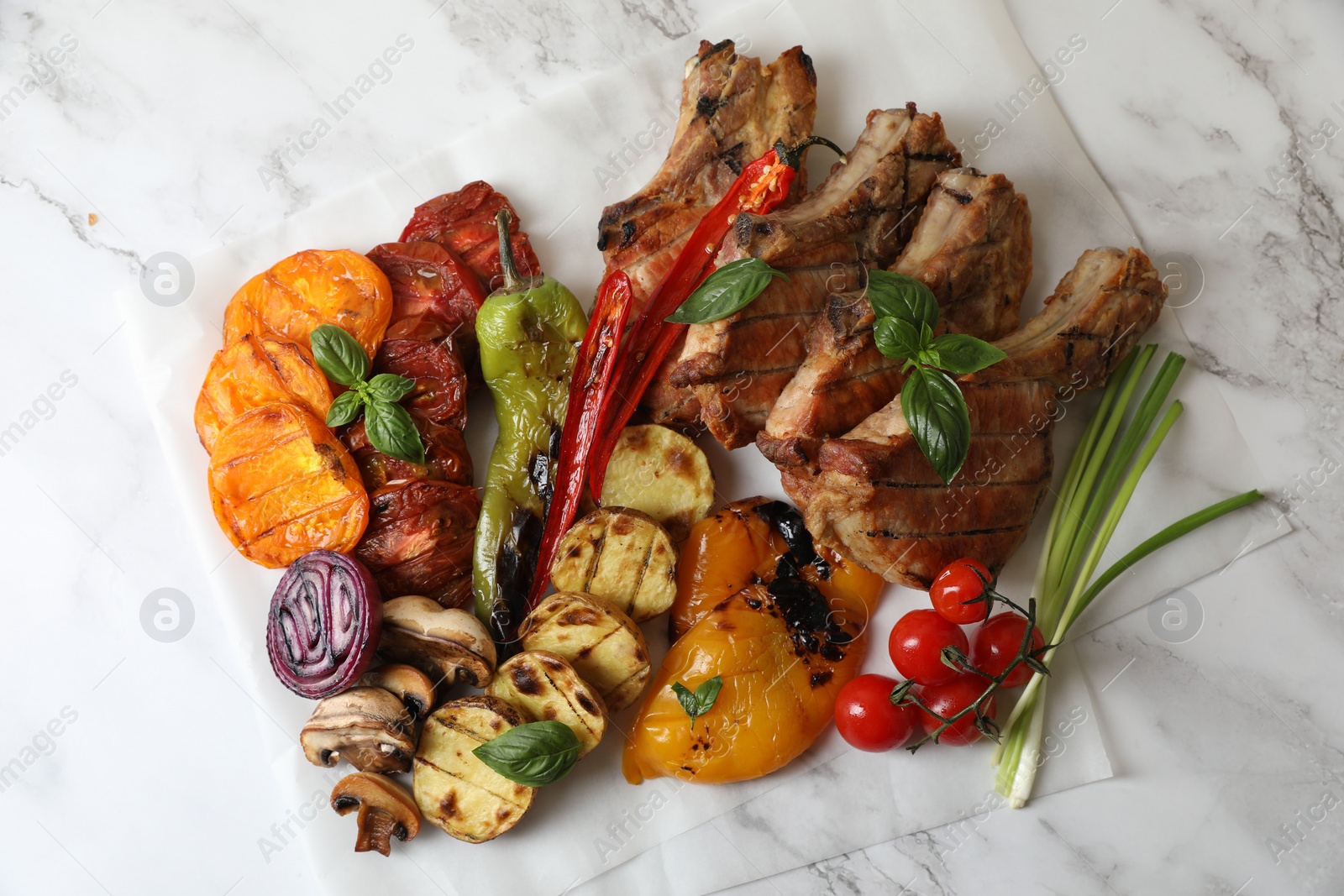 Photo of Delicious grilled meat and vegetables on white marble table, top view