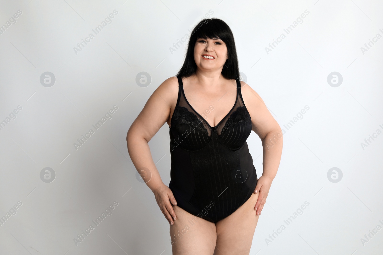 Photo of Beautiful overweight woman in black underwear on light background. Plus-size model