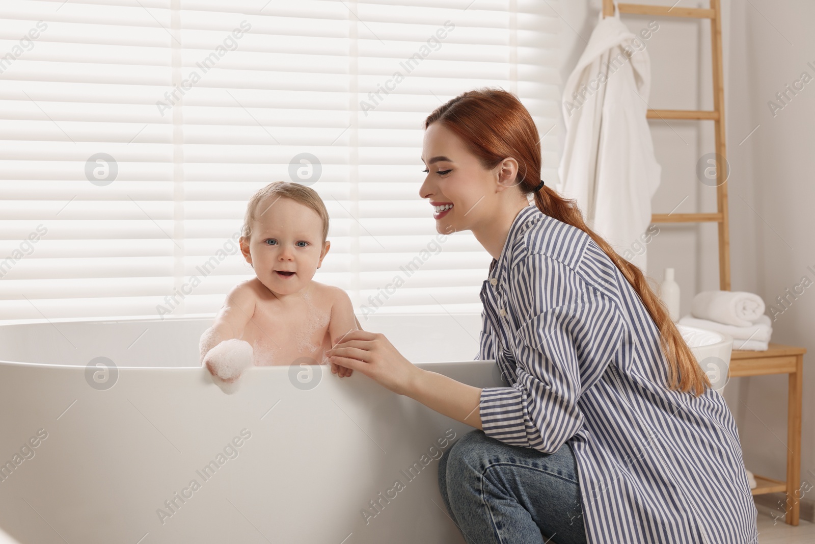 Photo of Mother washing her little baby in tub at home