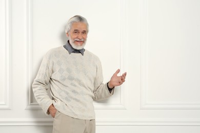 Photo of Portrait of handsome senior man near white wall. Space for text