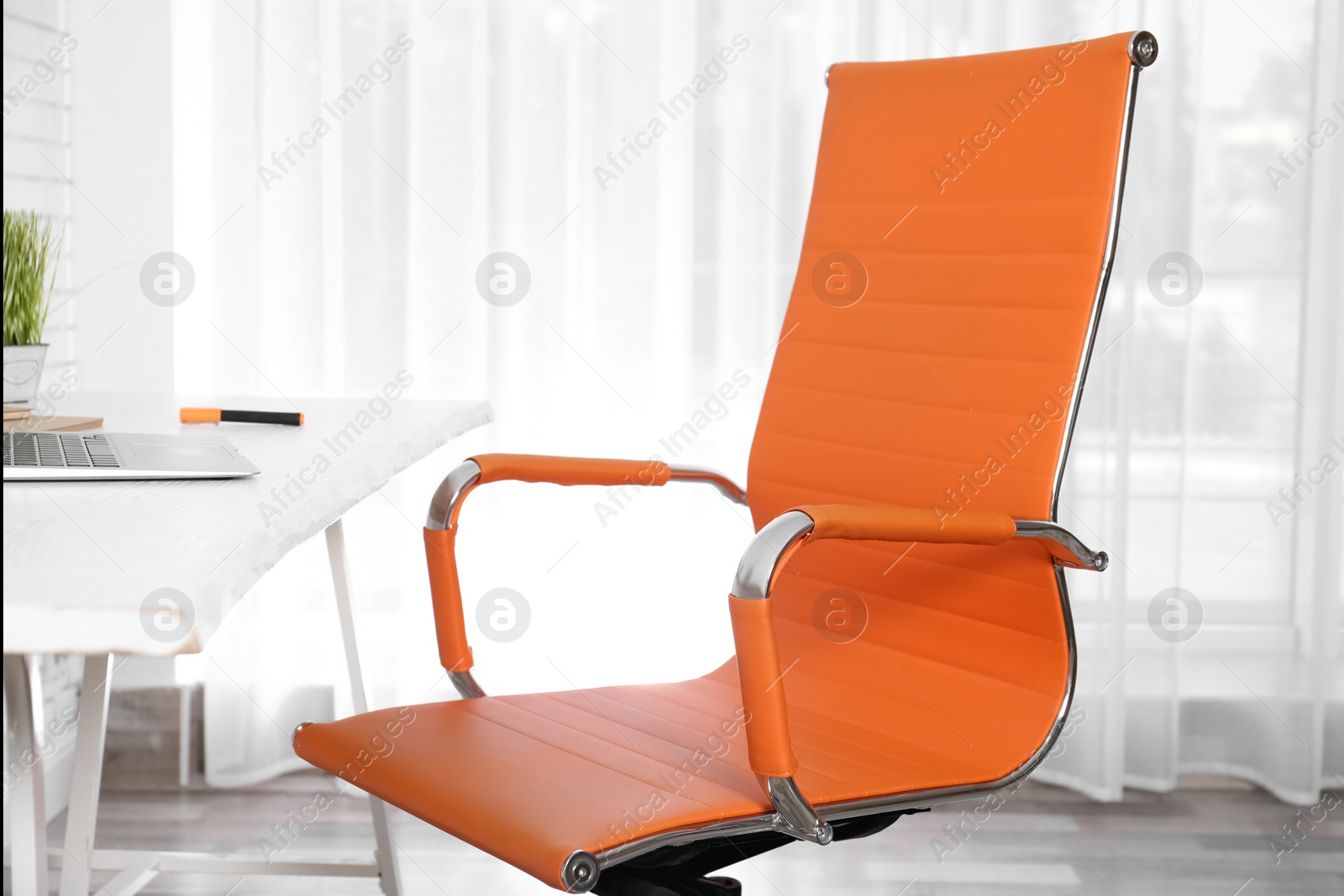 Photo of Comfortable workplace with office chair and wooden table