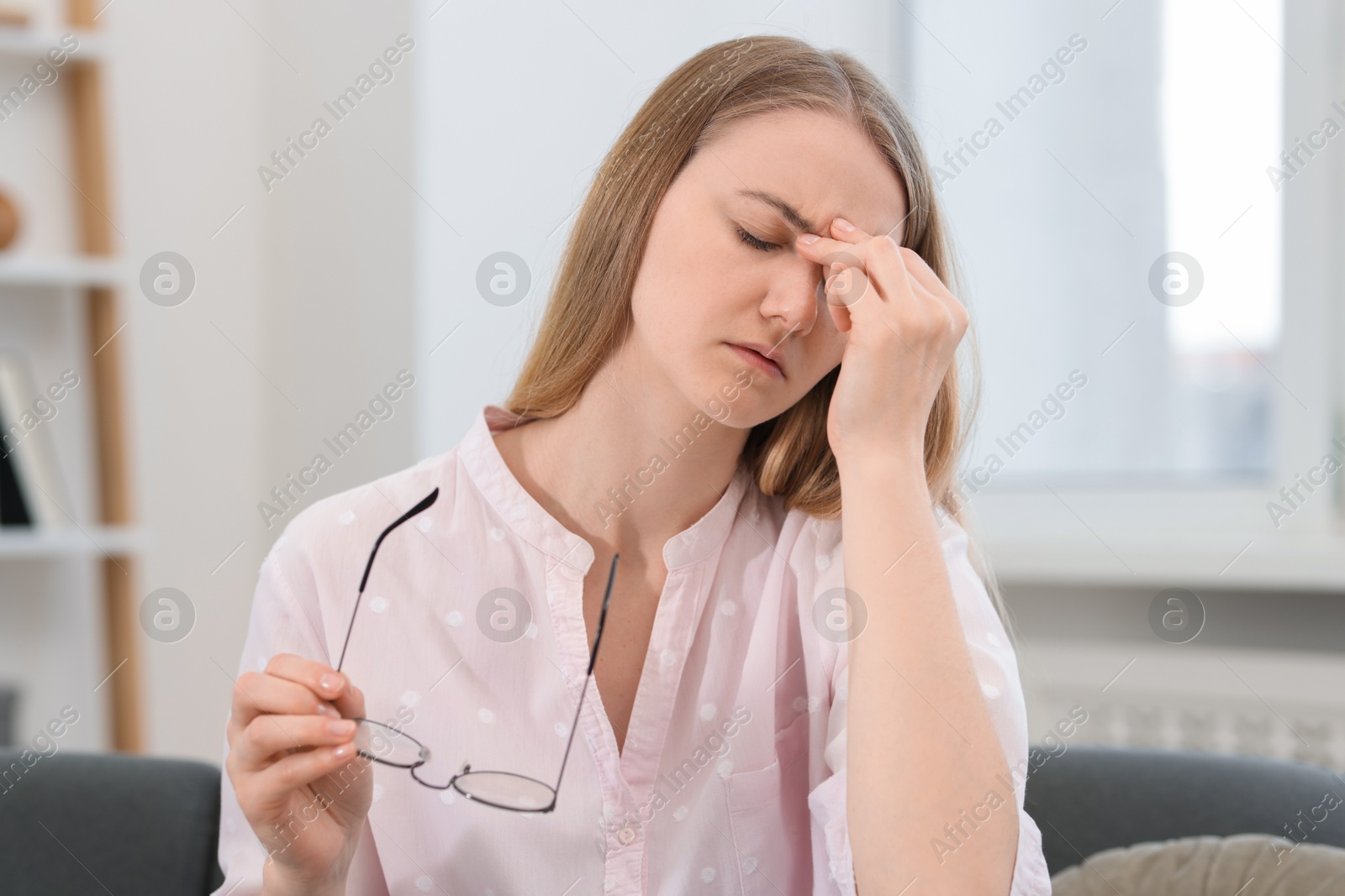 Photo of Overwhelmed young woman with glasses suffering from headache at home