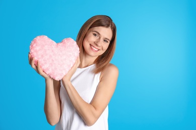 Photo of Portrait of woman with decorative heart shaped pillow on color background. Space for text