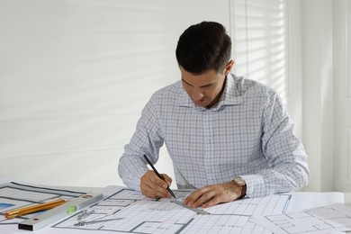 Photo of Architect working with construction drawings in office