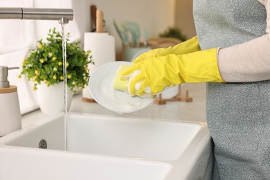 Photo of Housewife washing plate in kitchen sink, closeup