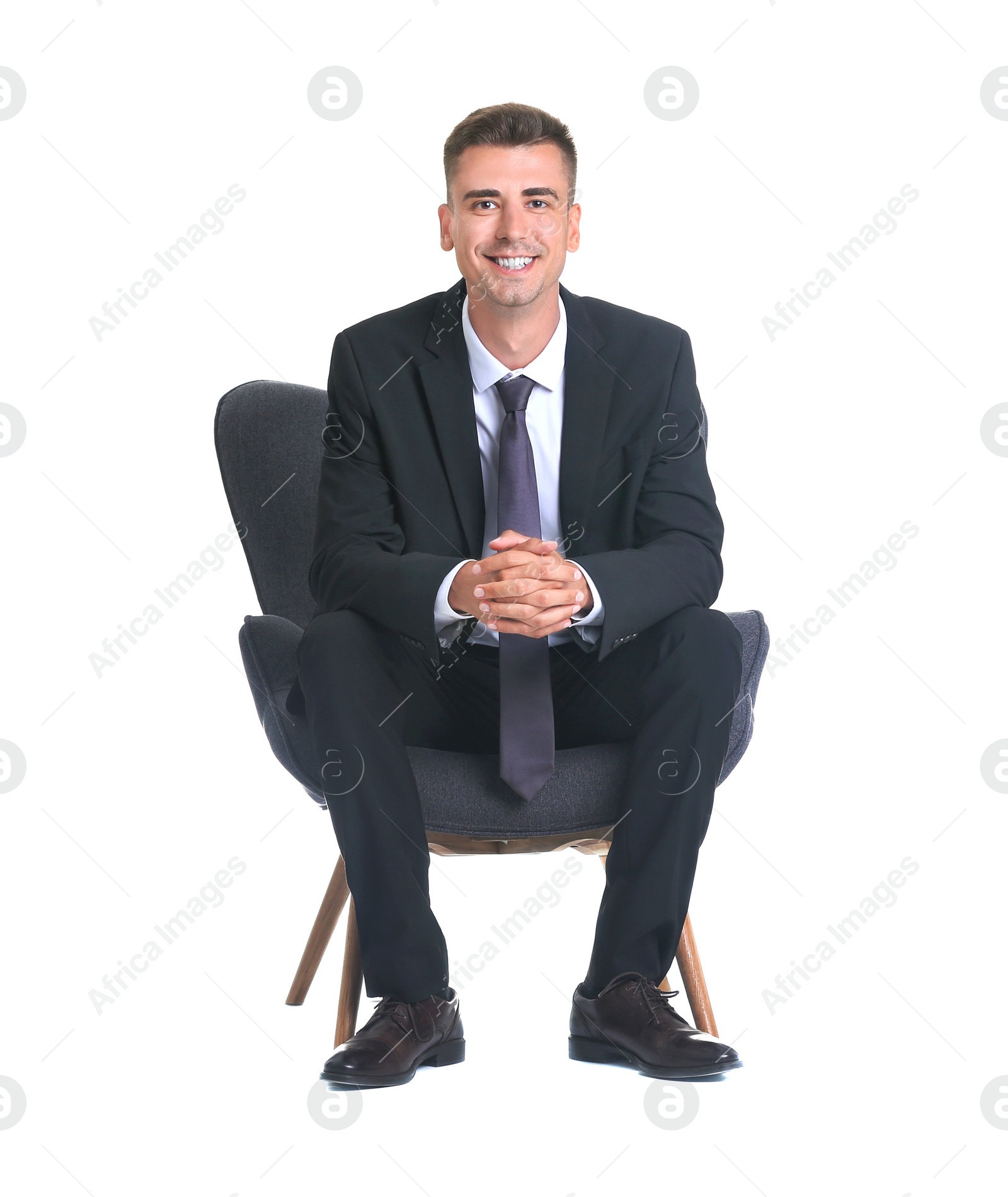 Photo of Handsome young man in suit sitting in armchair on white background