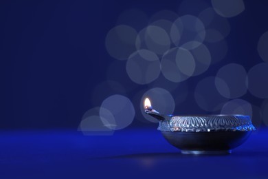 Photo of Lit diya lamp on dark table, space for text. Diwali celebration
