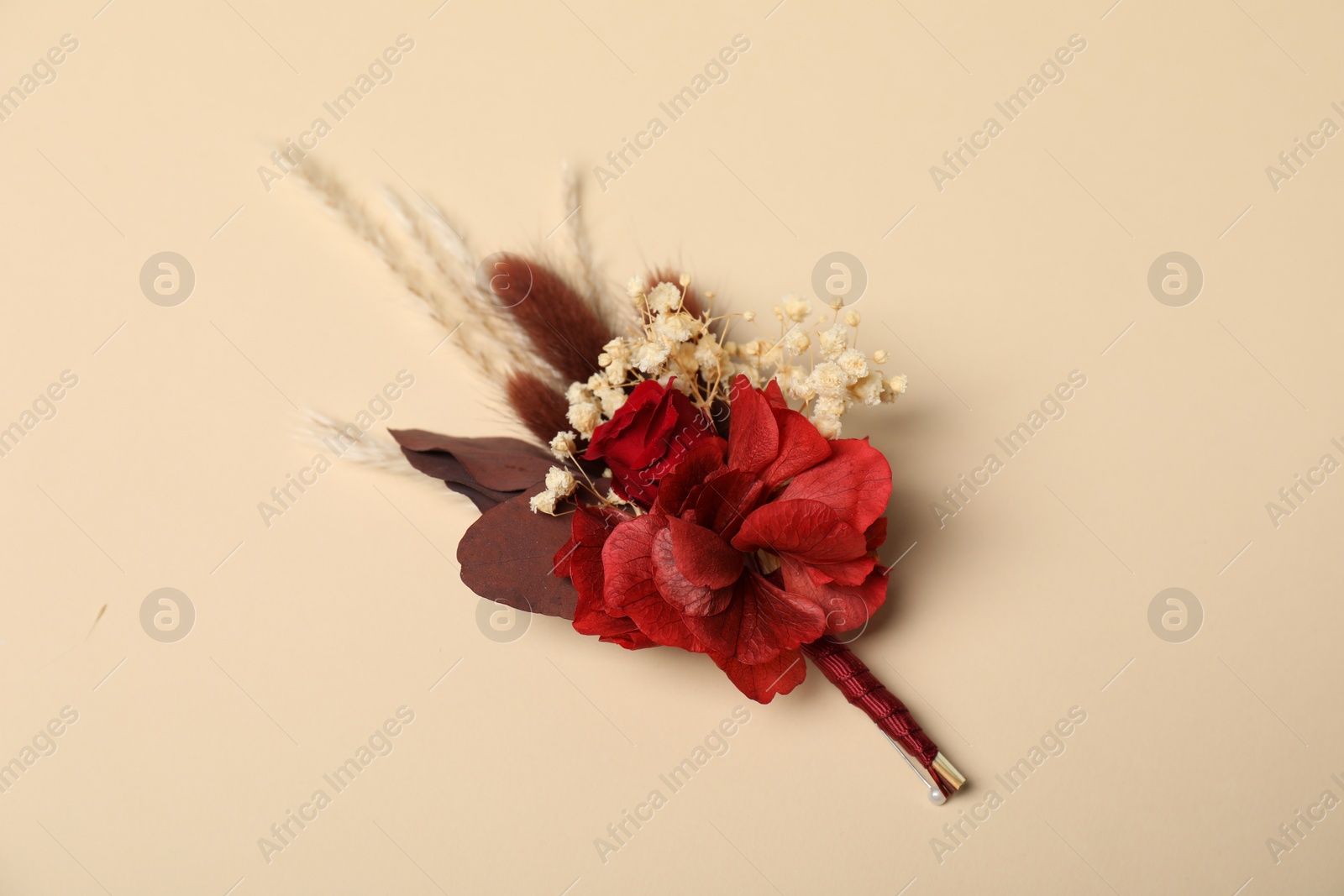 Photo of Stylish red boutonniere on beige background, top view
