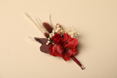 Photo of Stylish red boutonniere on beige background, top view