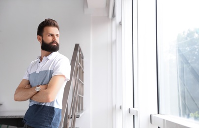 Photo of Young bearded man near window. Working in office