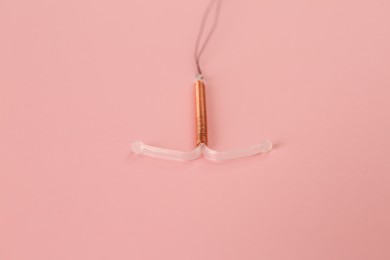 Photo of Copper intrauterine contraceptive device on light pink background