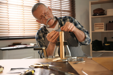 Man sewing piece of leather in workshop