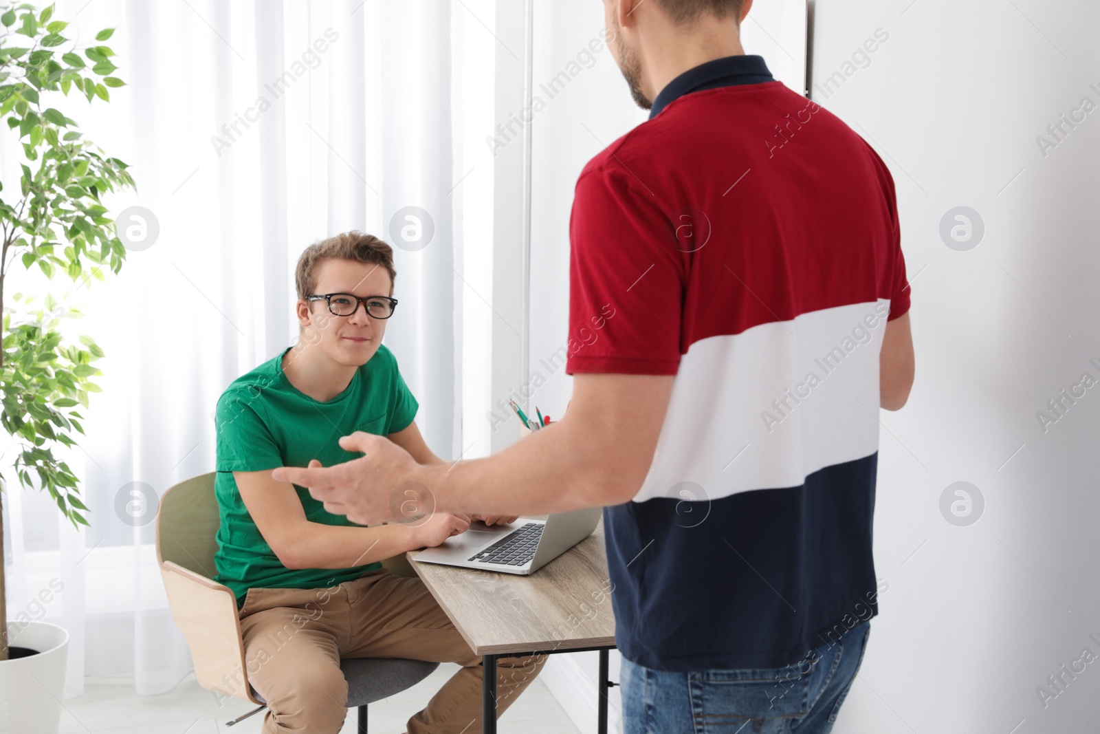 Photo of Father talking with his teenager son at home