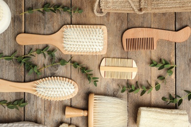 Photo of Flat lay composition with hair brushes and combs on wooden background