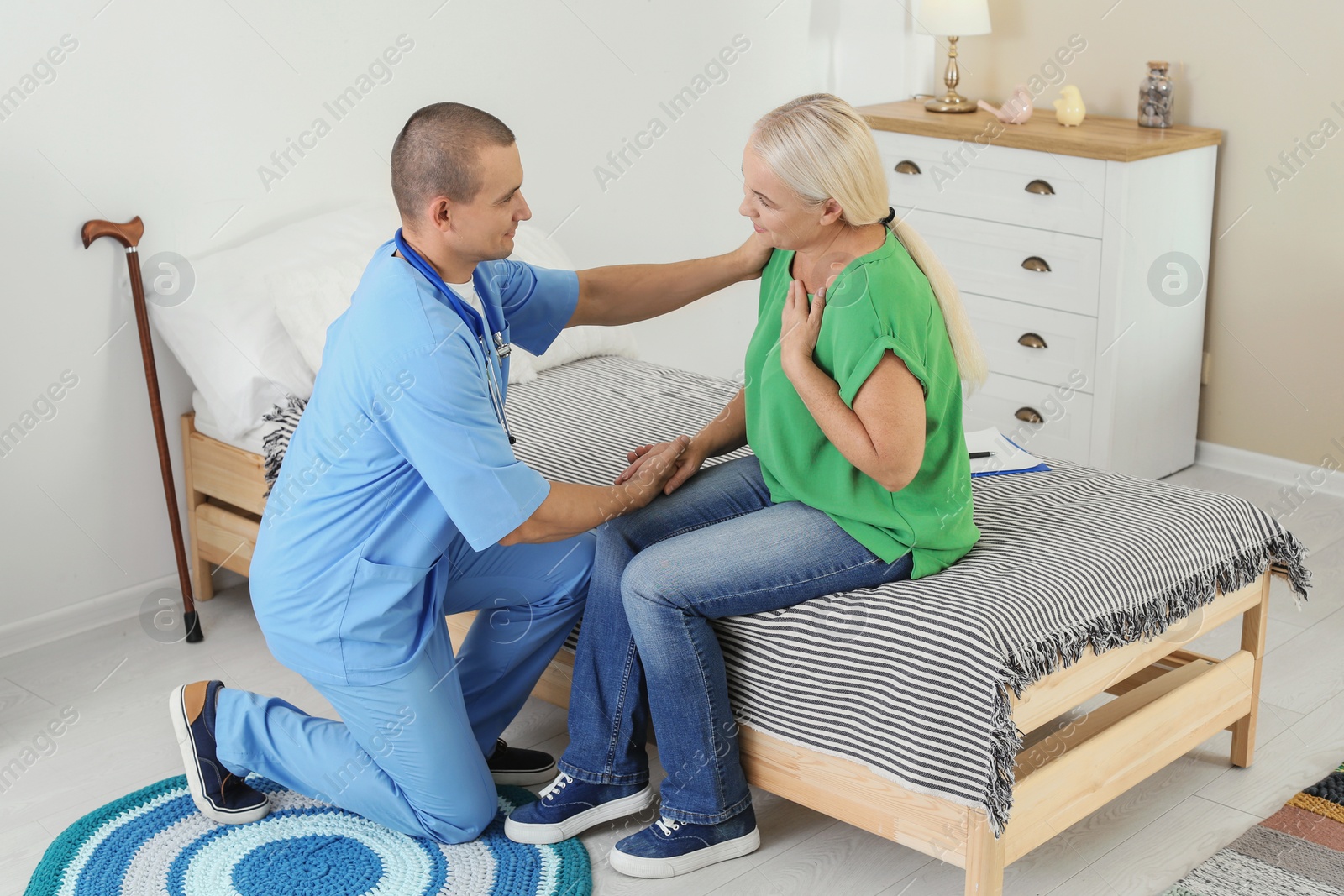 Photo of Male medical assistant consulting female patient during home visit