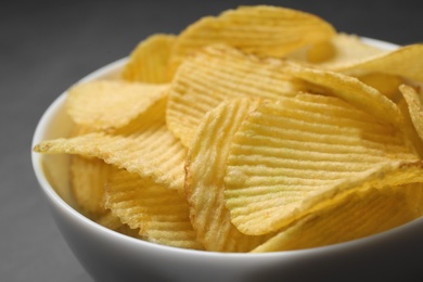 Photo of Tasty potato chips in bowl, closeup view