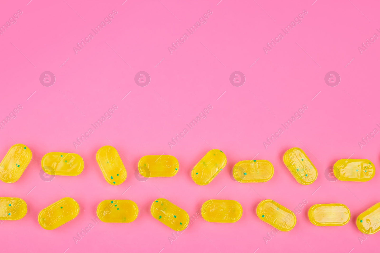 Photo of Many delicious lemon drops on pink background, flat lay. Space for text