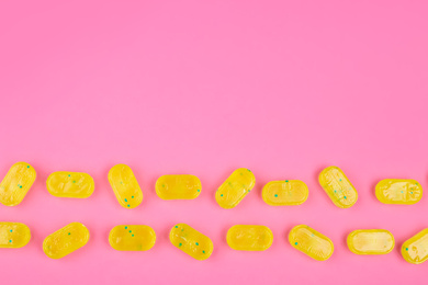 Photo of Many delicious lemon drops on pink background, flat lay. Space for text