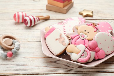 Plate of baby shower cookies and accessories on white wooden table