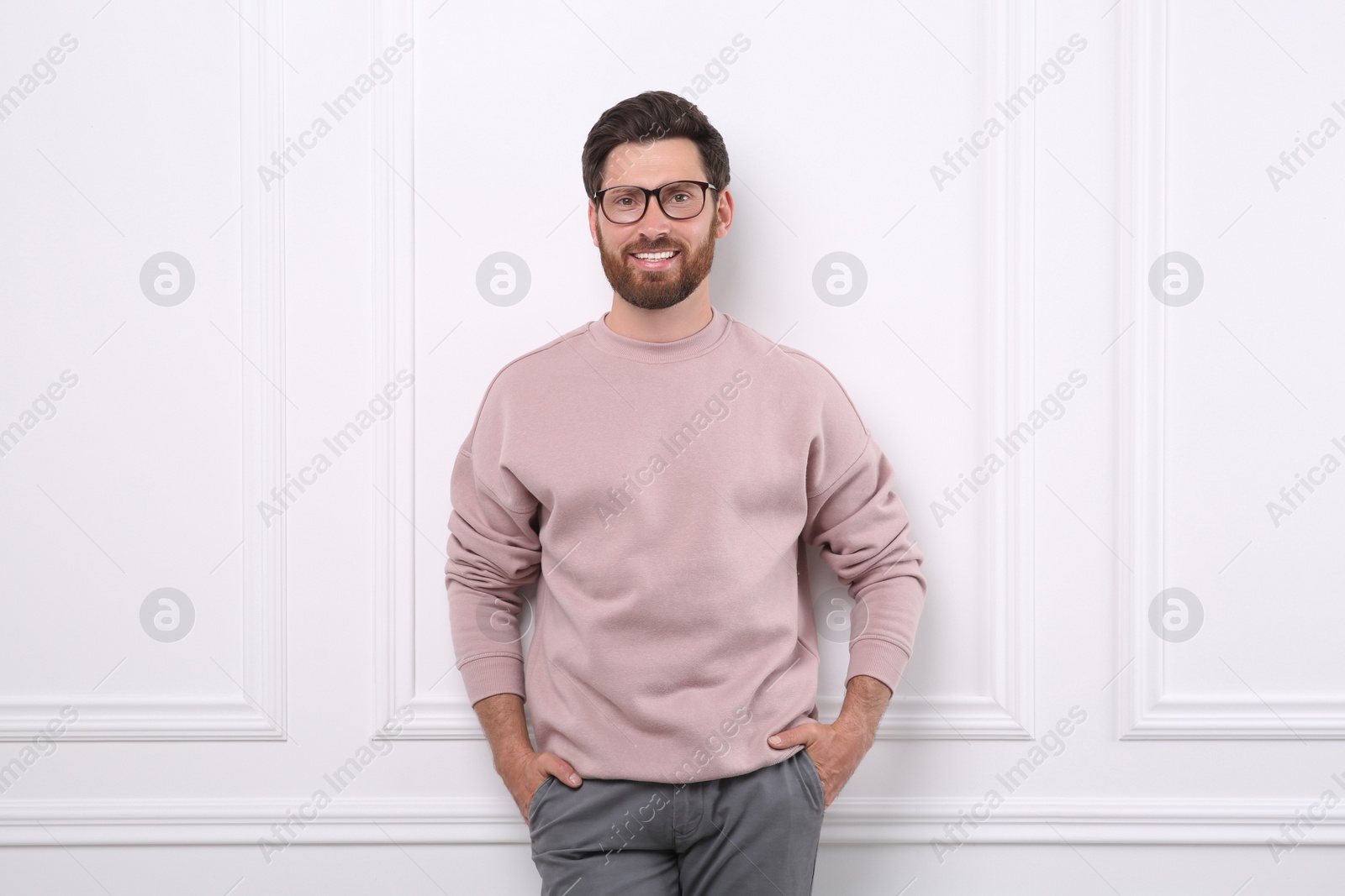 Photo of Portrait of handsome man in glasses near white wall