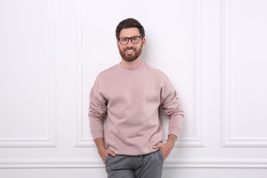 Portrait of handsome man in glasses near white wall