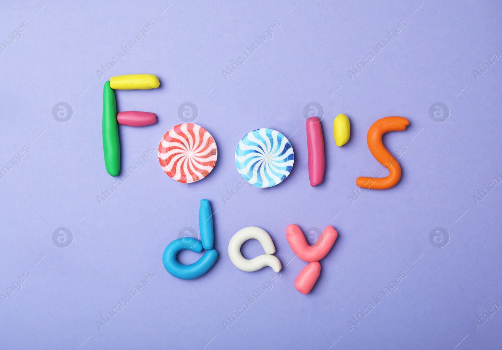 Photo of Flat lay composition with words FOOL'S DAY on violet background. April holiday