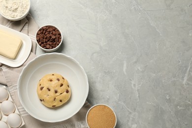 Fresh dough and different ingredients for cooking chocolate chip cookies on light grey marble table, flat lay. Space for text