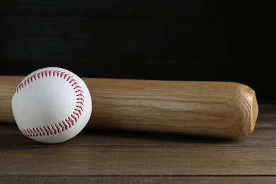 Photo of Baseball bat and ball on wooden table. Sports equipment