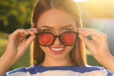 Photo of Beautiful young smiling woman in sunglasses outdoors