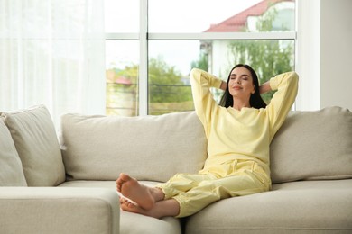 Photo of Young woman relaxing on sofa at home, space for text