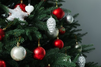 Photo of Beautifully decorated Christmas tree on grey background, closeup